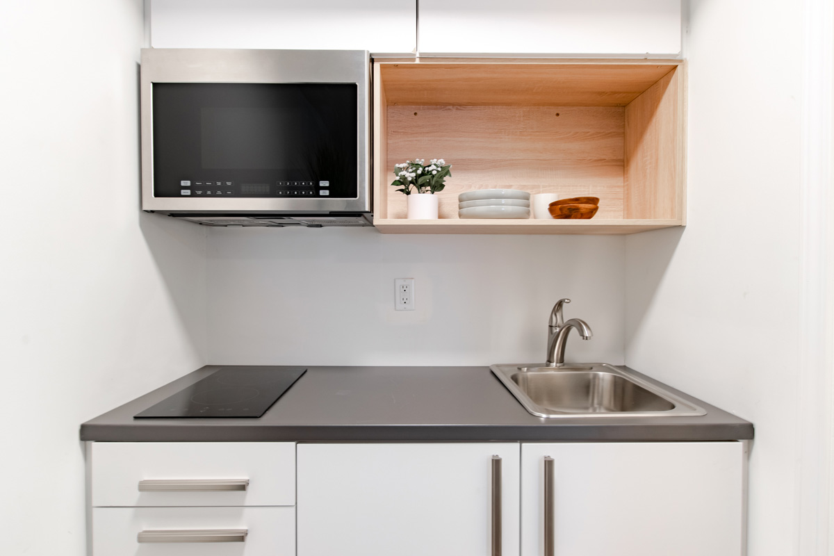 Studio kitchenette with cupboards, microwave, and stovetop
