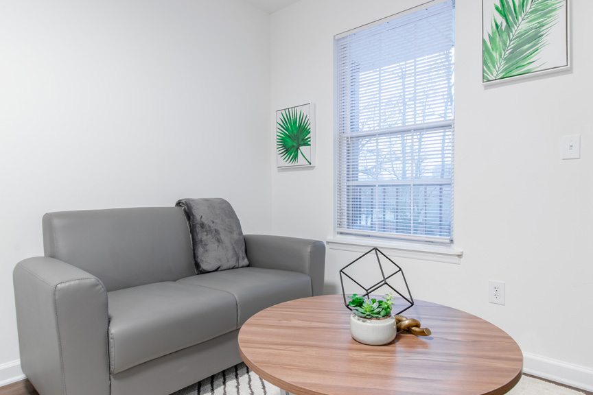 Corner of studio apartment with sofa and large window